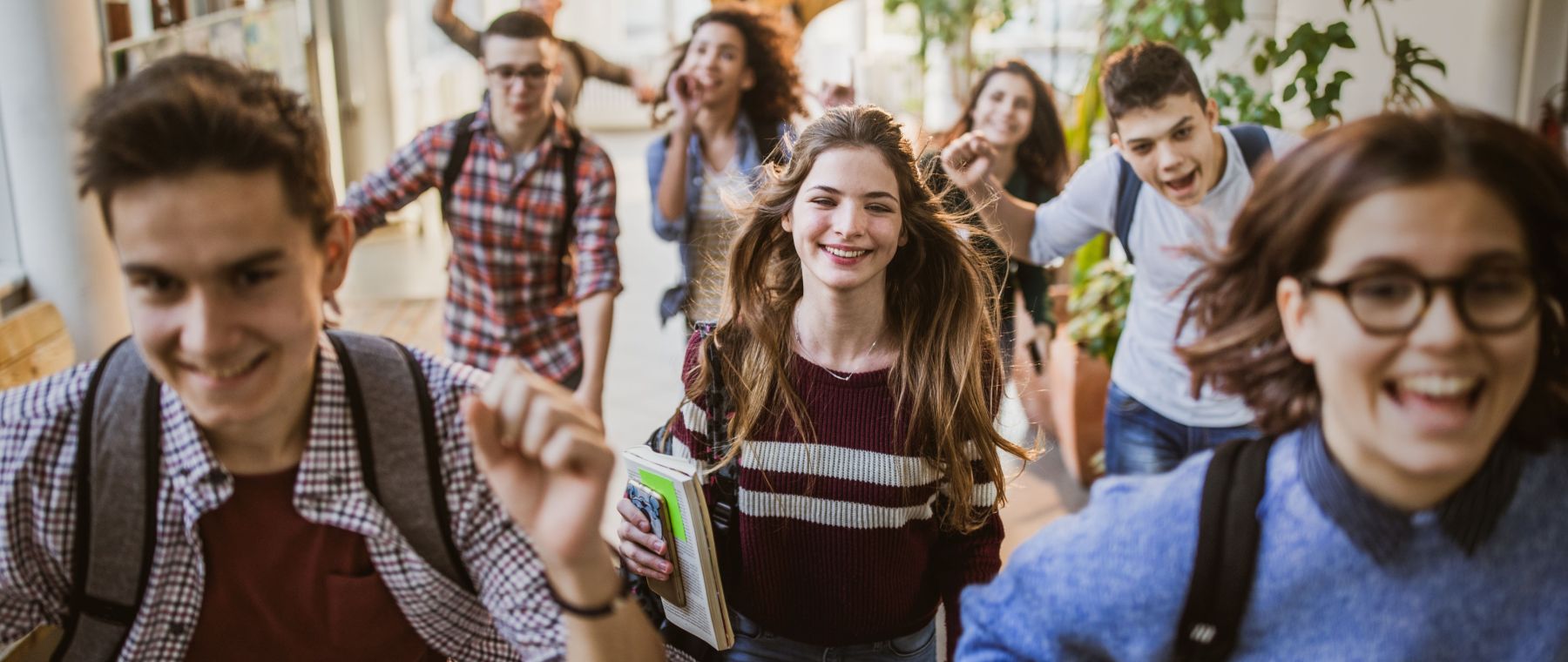 Große Gruppe fröhlicher Schüler läuft durch den Schulflur